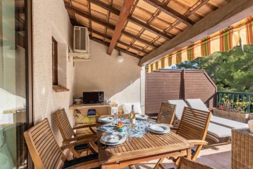 une table et des chaises en bois sur une terrasse dans l'établissement Superb apartment with terrace and private pool, à Bandol