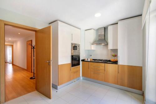 a kitchen with white walls and wooden cabinets at MyOasis II - Algarve in Olhão