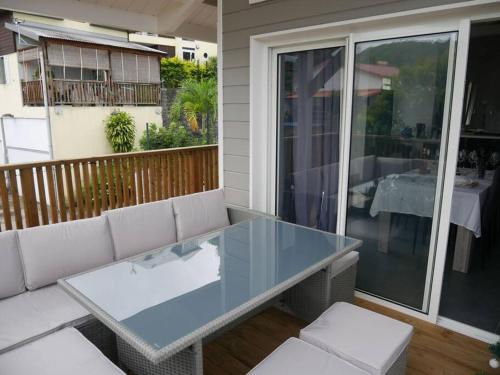 a glass table and chairs on a balcony with a table at Villa Entre-Deux Centre in LʼEntre-Deux