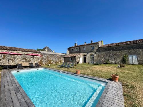 - une piscine en face d'une maison en pierre dans l'établissement Les Tourelles, à Saint-Christoly-Médoc