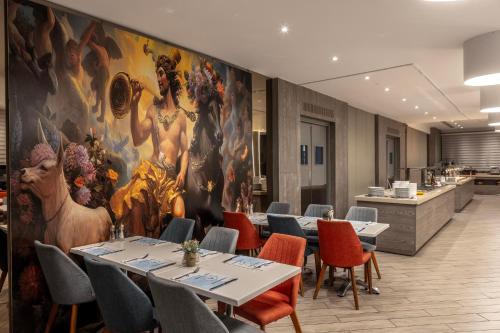 a restaurant with tables and chairs and a large painting on the wall at Park Beach Hotel in Limassol