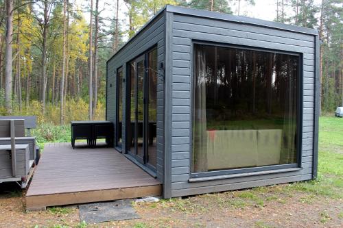 a black tiny house on a wooden deck at Minimaja saunaga vaatega männimetsale in Syytme