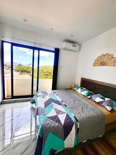 a bedroom with a bed and a large window at Cozy Seaview Penthouse in Flic-en-Flac