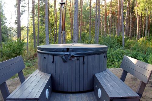 a large trash can sitting next to two benches at Minimaja saunaga vaatega männimetsale in Syytme