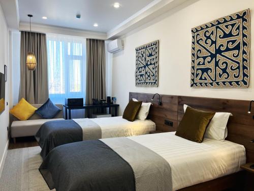 una habitación de hotel con dos camas y un sofá en Akjola Hotel, en Bishkek