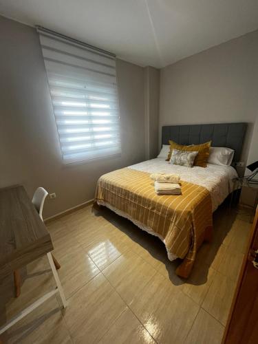 a bedroom with a bed with a yellow blanket and a window at Apartamentos Modern Homes in Chiclana de la Frontera