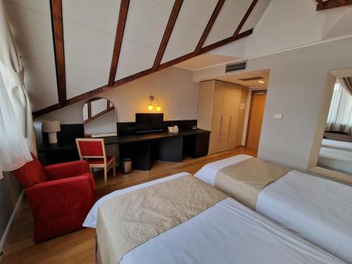 a hotel room with two beds and a red chair at Hotel Sunny Hill in Cluj-Napoca