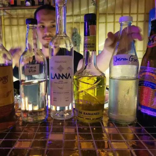 a man standing behind a table with bottles of alcohol at Stash in Bangkok