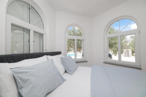 a white bedroom with two windows and a bed at House Anna in Drage