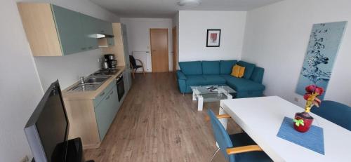 a small living room with a blue couch and a kitchen at Pension am Wald in Gößweinstein