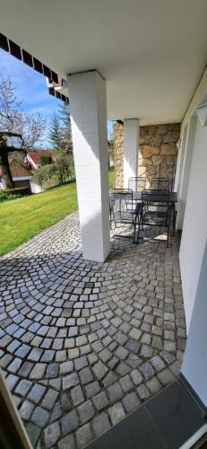 a stone patio with two benches on a house at Pension am Wald in Gößweinstein
