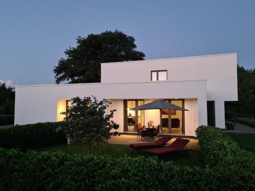 une maison blanche avec deux chaises et un parasol dans l'établissement Eilers, Katja Lilly, Ferienwohnung Lilly, à Varel