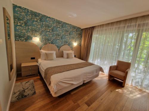 a bedroom with a large bed and a chair at Hotel Sunny Hill in Cluj-Napoca