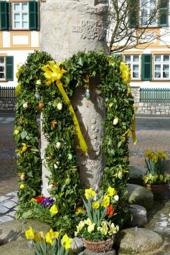 a wreath with flowers and a bow on a statue at Luisenhof in Geisfeld