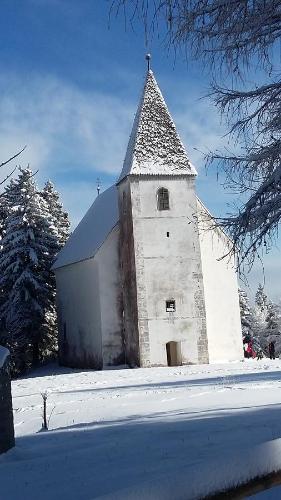 a white church with a steeple in the snow at Apartments Akacijev Izvir in Miklavž na Dravskem Polju
