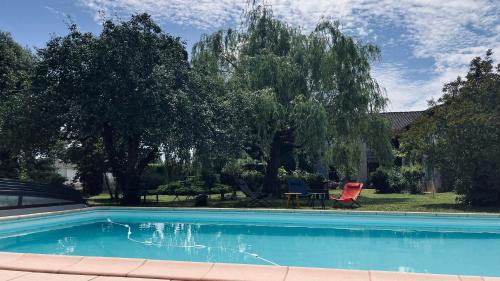 a swimming pool with a table and two chairs and trees at La vieille ferme de Gaillac in Gaillac
