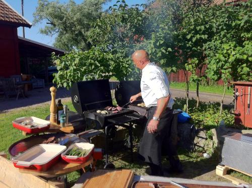 a man cooking food on a grill in a yard at Äventyrsgårdens Vandrarhem, Kinnekulle in Källby