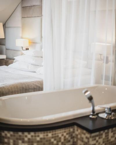 a bathroom with a bath tub and a bed at Grand Hotel Boutique in Rzeszów