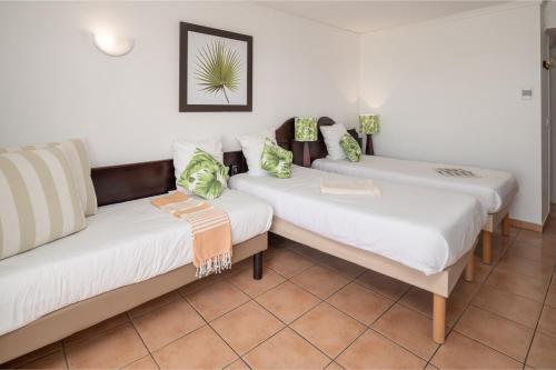 two beds in a room with white walls at Village Pierre & Vacances Sainte Anne in Sainte-Anne
