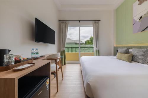 a hotel room with a bed and a desk and a bed and a window at Upstairs at Ton Ton in Bangkok