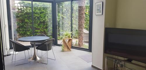 salon ze stołem, krzesłami i telewizorem w obiekcie Le Palmier, Maison de ville, 3 chambres et jardin/terrasse w mieście Blois