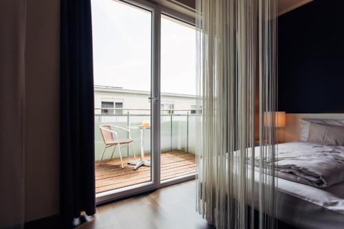 a bedroom with a bed and a balcony with a desk at harry's home Linz-Urfahr hotel & apartments in Linz