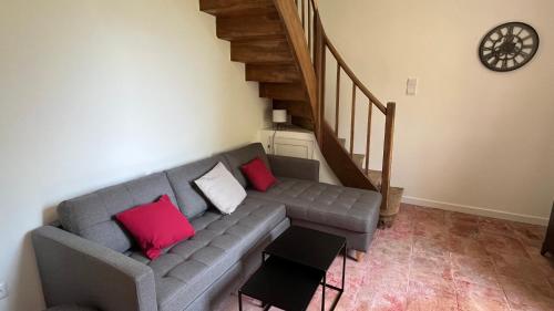 a living room with a gray couch with two red pillows at La vieille ferme de Gaillac in Gaillac