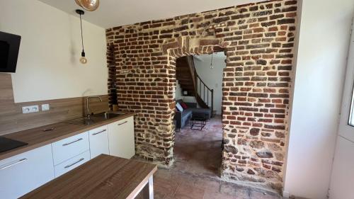 a kitchen with a brick wall and a stairway at La vieille ferme de Gaillac in Gaillac