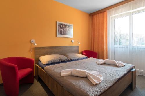 a bedroom with a bed and a red chair at Penzion Vápenka in Horní Maršov