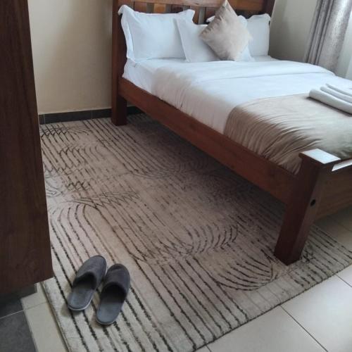 a bedroom with a bed with a pair of shoes on a rug at RCMRD EXECUTIVE SUITES in Nairobi