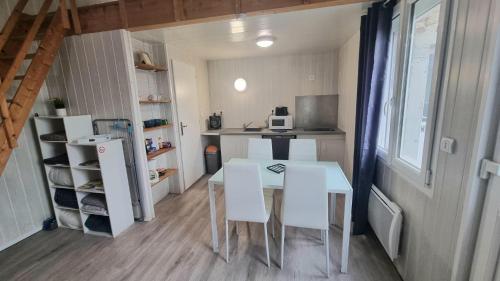 a small kitchen with a table and white chairs at La Mezzanine - 2-4 pers - Centre-Ville in Brassac-les-Mines