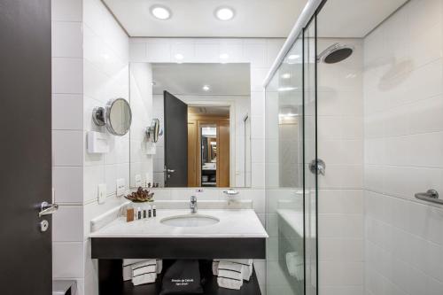 a white bathroom with a sink and a shower at Meliá Campinas in Campinas