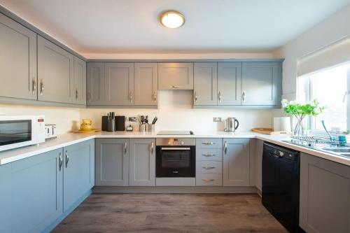 a kitchen with white cabinets and a black appliance at City centre 4 Bed house FREE parking walk to town in Cardiff