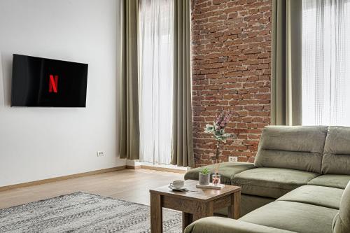 a living room with a couch and a brick wall at ARI Central Grand Apartments - Luxurious Stay in Arad