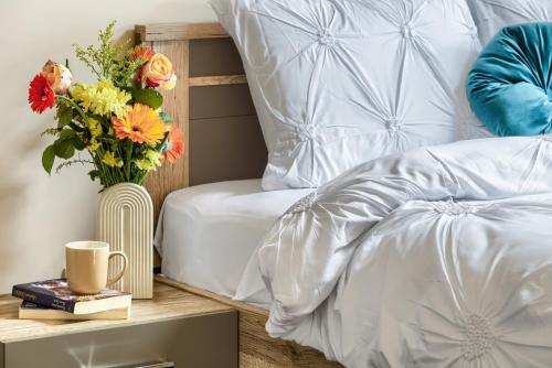 a bedroom with a bed with a vase of flowers on a table at ARI Central Grand Apartments - Luxurious Stay in Arad