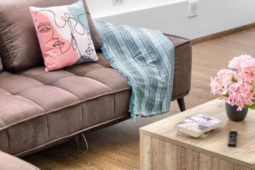 a brown couch with a pink pillow and a coffee table at ARI Central Grand Apartments - Luxurious Stay in Arad