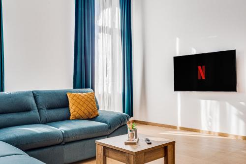 a living room with a blue couch and a table at ARI Central Grand Apartments - Luxurious Stay in Arad