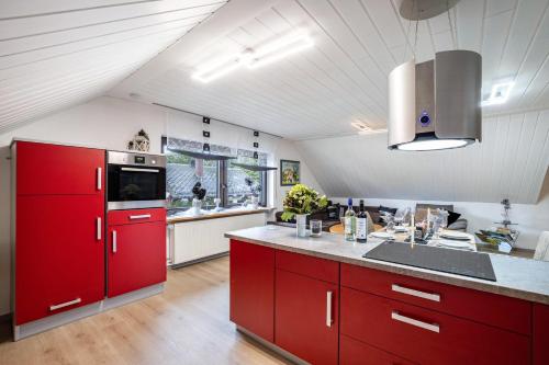 a large kitchen with red cabinets and a sink at Ferienwohnung Familie Süttner in Nagel