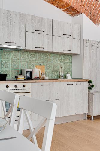 a kitchen with white cabinets and green tiles at ARI Central Grand Apartments - Luxurious Stay in Arad