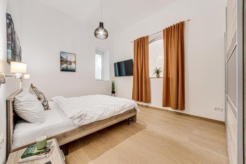 a white bedroom with a bed and a tv at ARI Central Grand Apartments - Luxurious Stay in Arad