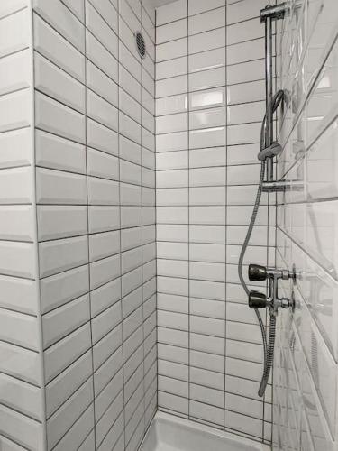 La salle de bains est pourvue d'une douche et de murs carrelés blancs. dans l'établissement Studio 8 - proche tram, Bâle, autoroute, à Bourgfelden