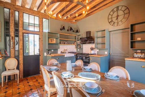 une cuisine avec une table, des chaises et une horloge dans l'établissement Manoir d'Exception - 20 Personnes - Piscine, Baby-Foot & Tapis de Course, à Coulaines
