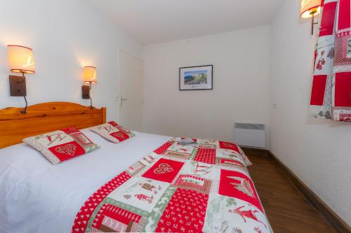 a bedroom with a bed with a red and white quilt at Résidence Goélia Le Sornin in Autrans