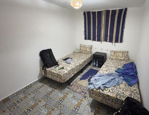 a small room with two beds and a chair at Surf & Skate in Taghazout