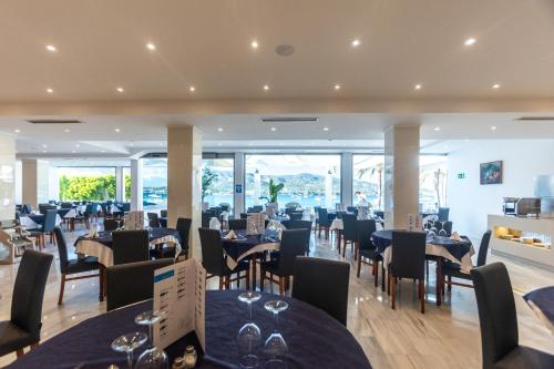a dining room with tables and chairs and windows at Seramar Hotel Comodoro Playa in Palmanova