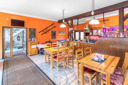 a restaurant with wooden tables and chairs and orange walls at Penzion Vápenka in Horní Maršov