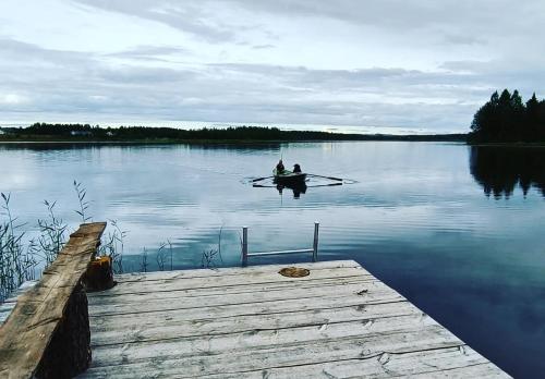 two people in a boat on the water near a dock at Goiglo Hotel & Hostel in Kuusamo