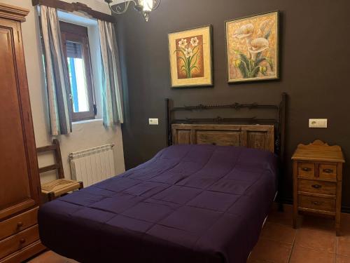 Un dormitorio con una cama morada y una ventana. en Casas Rurales Arcoiris, en Riópar