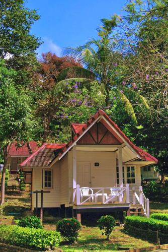 a small house with a porch and two white chairs at Pansand Resort in Ko Bulon Le
