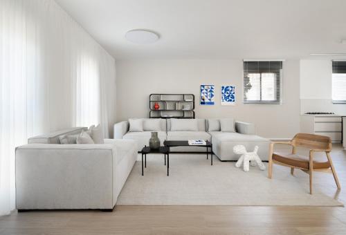 a living room with a white couch and a table at Adama by Sweett - Keren Hayesod Apartments in Jerusalem
